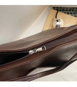 Detail of a smooth silver zipper on a dark brown leather commuter backpack for women