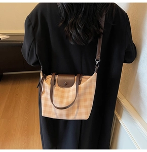 Detail showing high-density beige plaid canvas and dark brown leather trim on tote bag