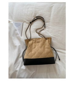 Close-up of quilted suede stitching and black leather trim on a chain strap tote bag