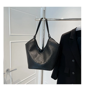 Detailed view of black woven texture on leather bucket bag with silver brand logo plate