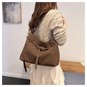 Detail of dark brown matte leather tote bag with buckle and adjustable strap