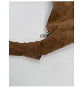Detail of reinforced knotted strap and silver zipper on brown vintage crossbody bag
