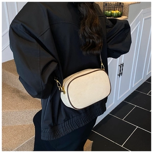 Detail of cream matte crossbody bag with brown leather trim and gold hardware accents