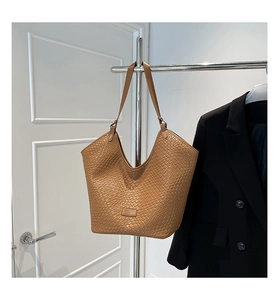 Close-up of brown woven leather tote bag with detailed texture on a stainless hanger
