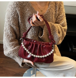 Détail du sac en cuir verni plissé bordeaux avec chaîne de perles et poignée nouée