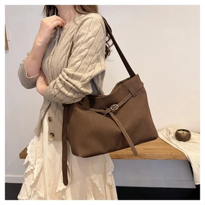 Detailed side view of brown suede tote bag worn by model in minimalist indoor setting