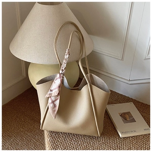 Dettaglio borsa tote beige in pelle martellata con foulard di seta a stampa geometrica