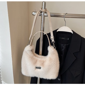 Détail du sac en fausse fourrure douce avec plaque logo en métal et bandoulière