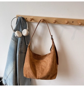 Detail of a brown suede tote bag featuring soft texture and minimalist metal zipper