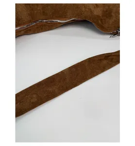 Macro shot of bronze suede bag detailing metal zipper and wide shoulder strap texture