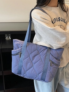 Blue quilted tote bag with diamond stitching and silver zipper pockets for women