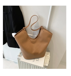 Detail of brown woven texture hobo tote bag with shoulder strap on white suitcase