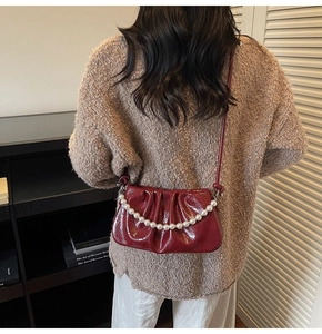 Détail du sac nuage plissé bordeaux avec chaîne en perles porté en bandoulière