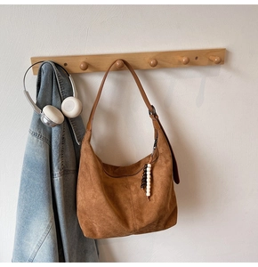 Brown faux suede hobo bag with colorful bead tassel hanging on a wooden wall hook