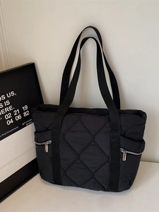 Black quilted tote bag with large diamond stitching and functional side zippers for daily use