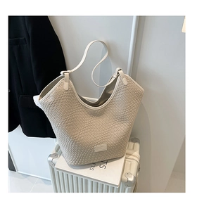Close-up of woven texture on beige tote bag with a branded leather tag and wavy edge