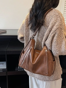 Brown vintage leather tote bag with tassel zippers shown on a model for casual commuting