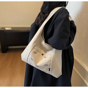 Detail-Rückansicht der cremeweißen Canvas-Tasche mit TELN-Stickerei und breitem Schultergurt