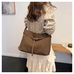 Detailed view of deep brown frosted leather tote bag with buckle strap on model