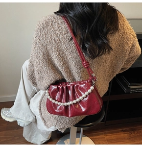 Detail of burgundy ruched faux leather bag with elegant large pearl chain strap
