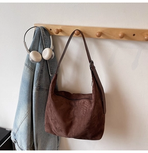 Detail of a brown suede hobo bag featuring a metal adjustment buckle and zipper closure