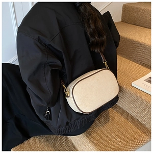 Detail view of retro beige canvas crossbody bag with brown leather trim on a model