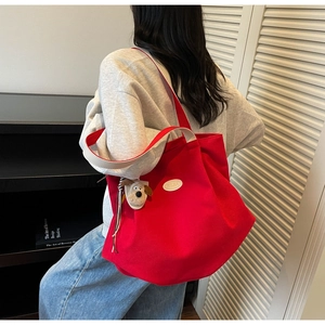 Detail of red canvas tote bag featuring white straps and cute puppy plush pendant charm