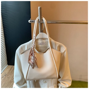 Dettaglio della borsa tote in pelle bianco crema con elegante foulard sulla maniglia