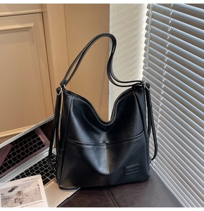 Detail of black leather tote bag with front pockets and elegant natural window light shadows
