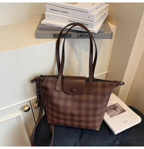 Detail of brown checkered tote bag with double handles and secure zipper closure