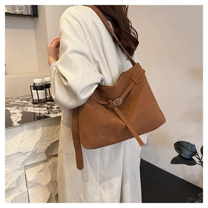 Detail shot of brown frosted leather tote bag with silver buckle on a stylish model