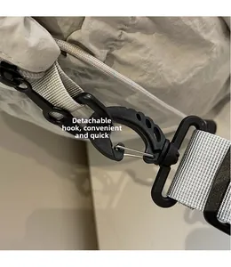 Detail of a light grey nylon bag showing a detachable black hook with silver metal clasp