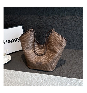 Macro detail of the dark brown woven texture and brand leather patch on the tote bag