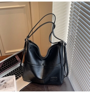 Detail of black faux leather tote bag with functional front pockets on a leather seat