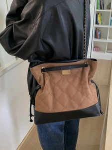 Brown quilted suede tote bag with black leather trim and gold chain strap shown on model