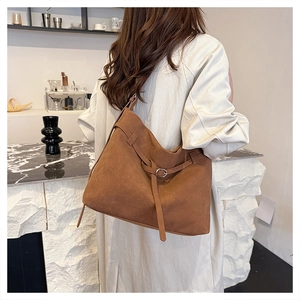 Caramel brown frosted leather tote bag with elegant buckle detail worn by a model