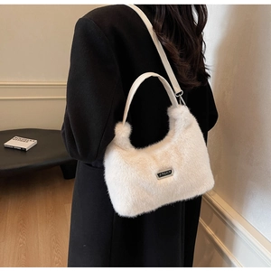 Détail de la texture du sac à main en fausse fourrure blanche avec logo en métal