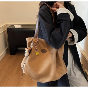 Detail of camel canvas tote with leather straps and decorative plush dog charm
