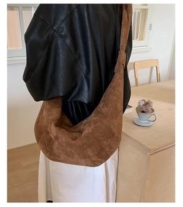 Brown faux suede crescent bag showing knot detail and drape on shoulder