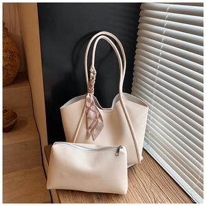 Dettaglio borsa tote color crema con foulard di seta sul manico e pochette coordinata