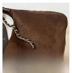 Detail der Metall- und Lederkette an einer dunkelbraunen Wildledertasche