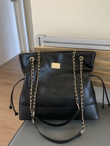 Quilted black tote bag with gold chain straps and spacious interior for daily use