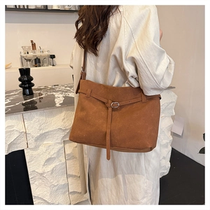 Detailed view of brown matte leather tote bag with silver buckle worn by a model