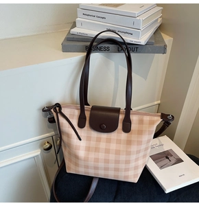 Close-up of beige plaid tote bag with brown leather handles and secure zip closure