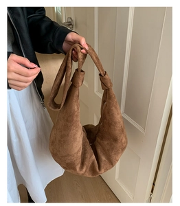 Close-up of brown suede hobo bag featuring decorative knotted shoulder strap detail
