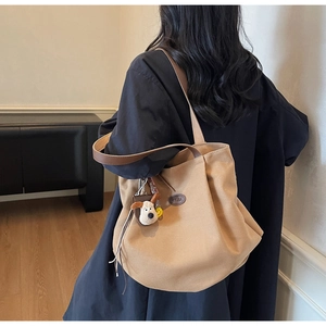 Detailed side view of khaki canvas tote bag with brown leather straps and puppy charm