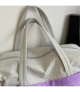 Detail of grey wrinkled fabric travel tote with purple plaid patchwork and durable handles