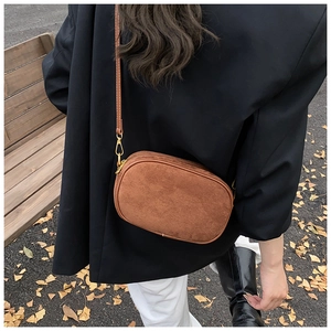 Detailed back view of a brown frosted suede small round crossbody bag in autumn outdoor