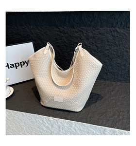 Detailed close-up of cream woven leather texture and square logo label on the tote bag
