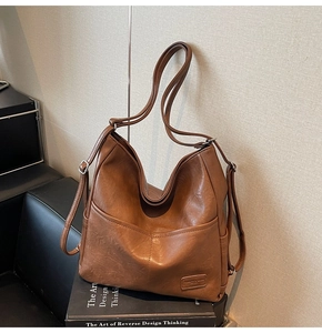 Close-up of brown synthetic leather tote bag with silver buckles and branded patch